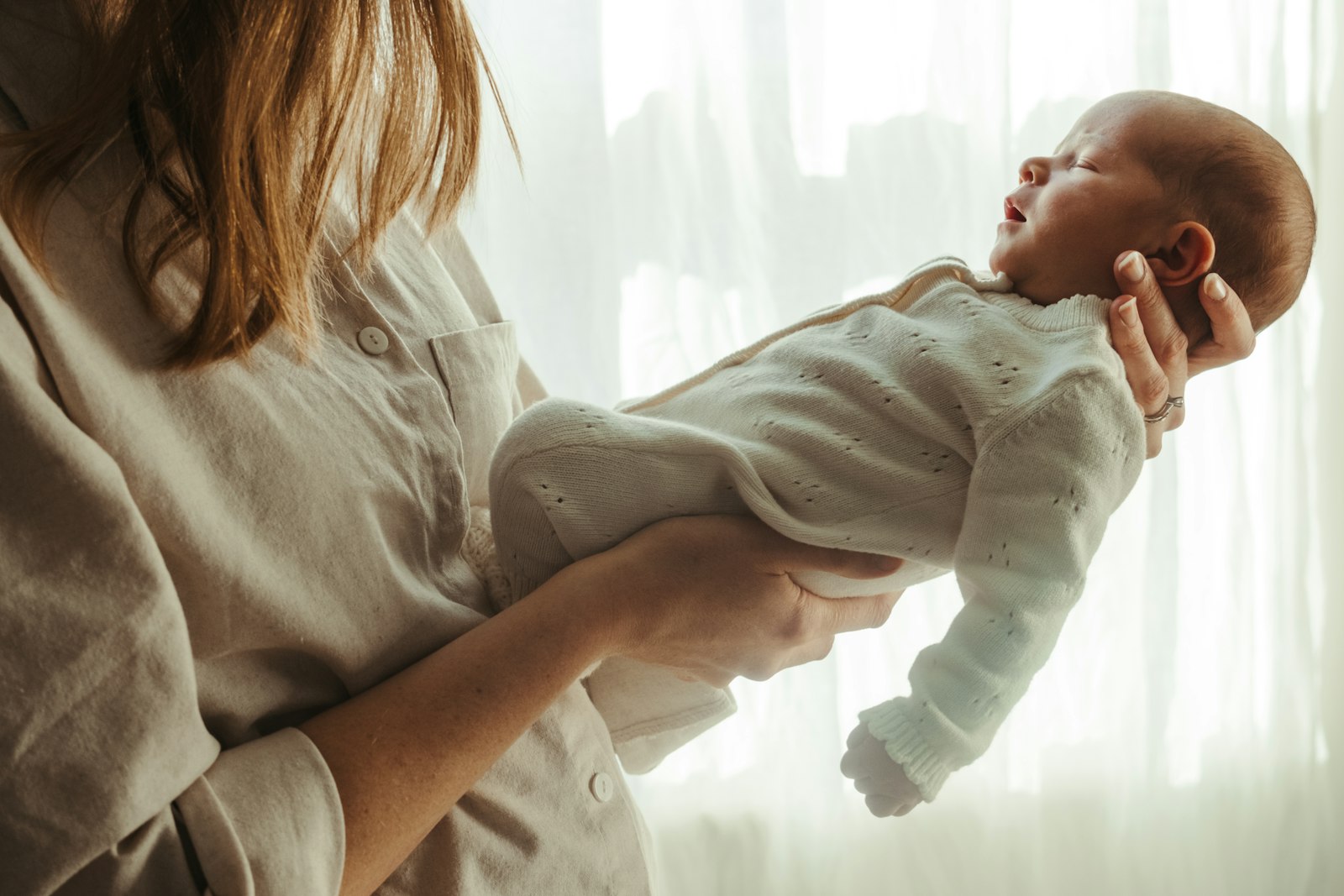Mutter hält ihr neugeborenes Baby am Fenster